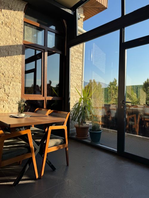 Free Cozy dining area with wooden chairs and natural light from large windows. Stock Photo