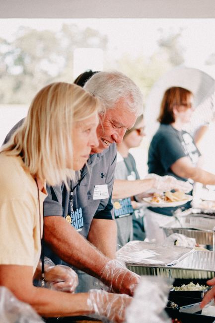 People serving food at a community church event outdoors.