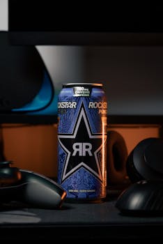 Rockstar energy drink can amongst gaming peripherals in a dimly lit setup.