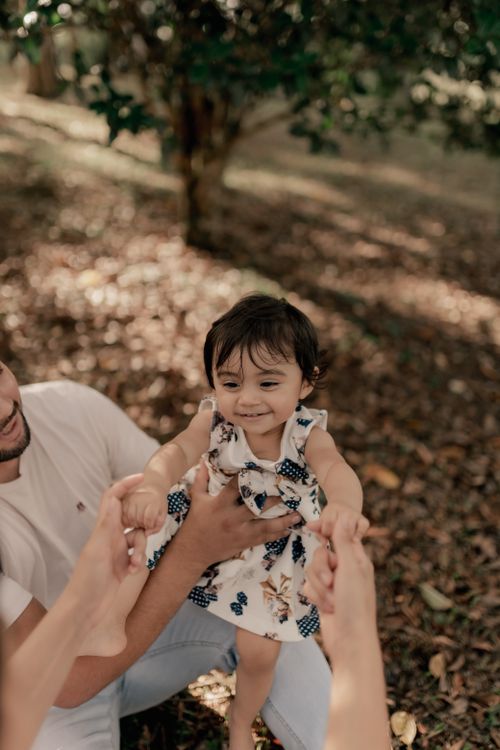Free A baby girl enjoys a playful moment outdoors in autumn light with her family. Stock Photo