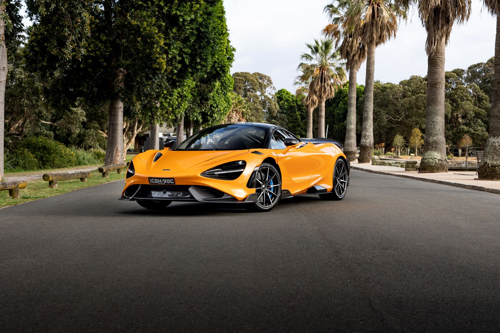 Papaya orange McLaren 765LT on a tree-lined road