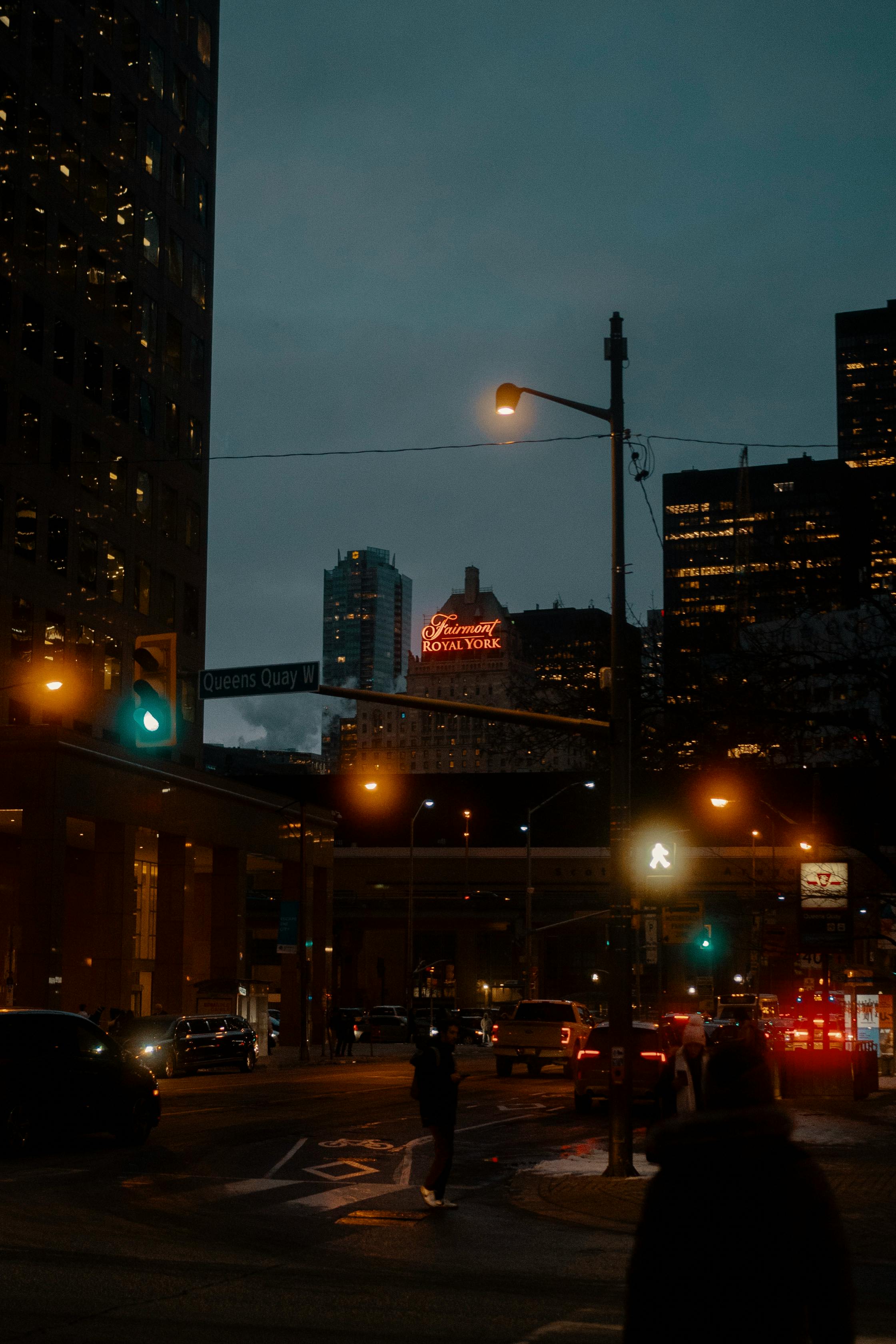 Night scene of a city street with the illuminated Royal York Hotel sign.