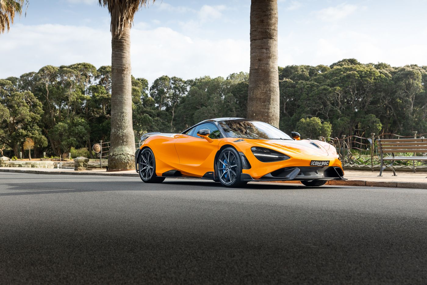 Papaya orange McLaren 765LT parked under palm trees