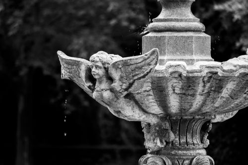 Free Artistic black and white photo of a decorative stone fountain with angelic details. Stock Photo