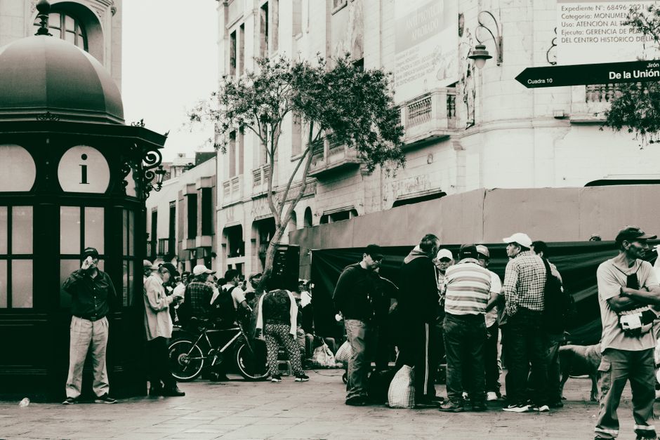 A bustling urban street scene with people gathered around an information kiosk.