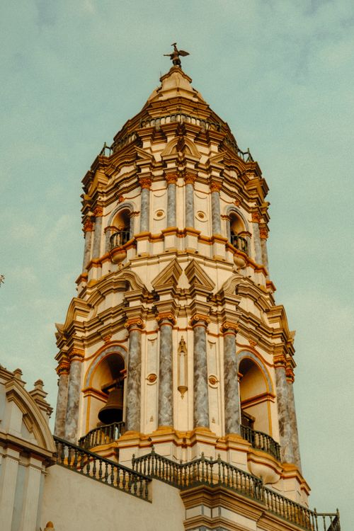 Free Baroque church tower with intricate details against a clear sky in Seville. Stock Photo