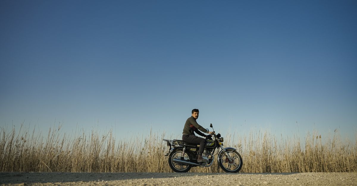 Rural Motorcycle Riding Man riding a motorcycle on rural road under blue sky · Free Stock Photo