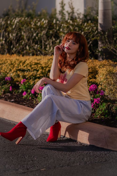 Free Stylish woman with red hair in red boots posing outside in spring. Stock Photo