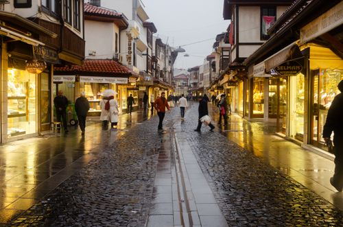 Free A rainy evening in a historic Konya street with people walking and illuminated shops. Stock Photo