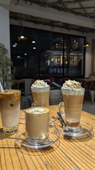 Assorted coffee drinks on a wooden table in a cozy café, perfect for a relaxing break.