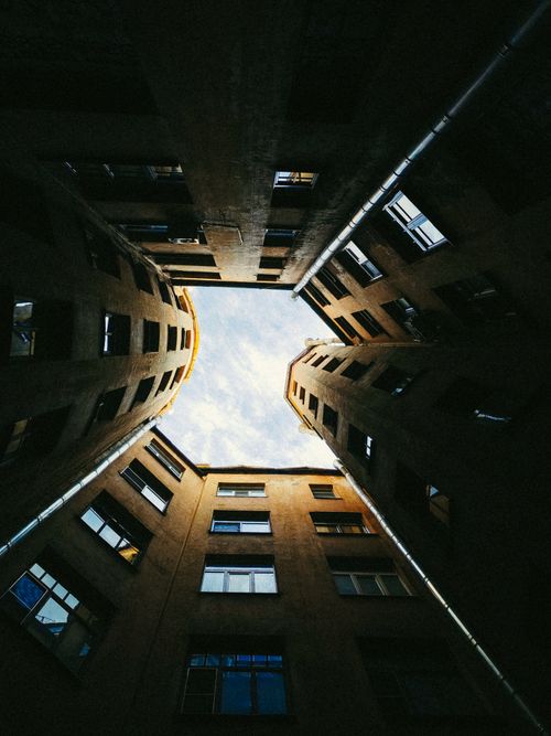 Free Unique upward view of a courtyard surrounded by high-rise buildings with a patch of sky visible through the top. Stock Photo
