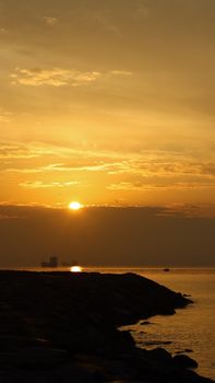 Serene sunset over ocean with distant ship. Vibrant golden hues fill the horizon.