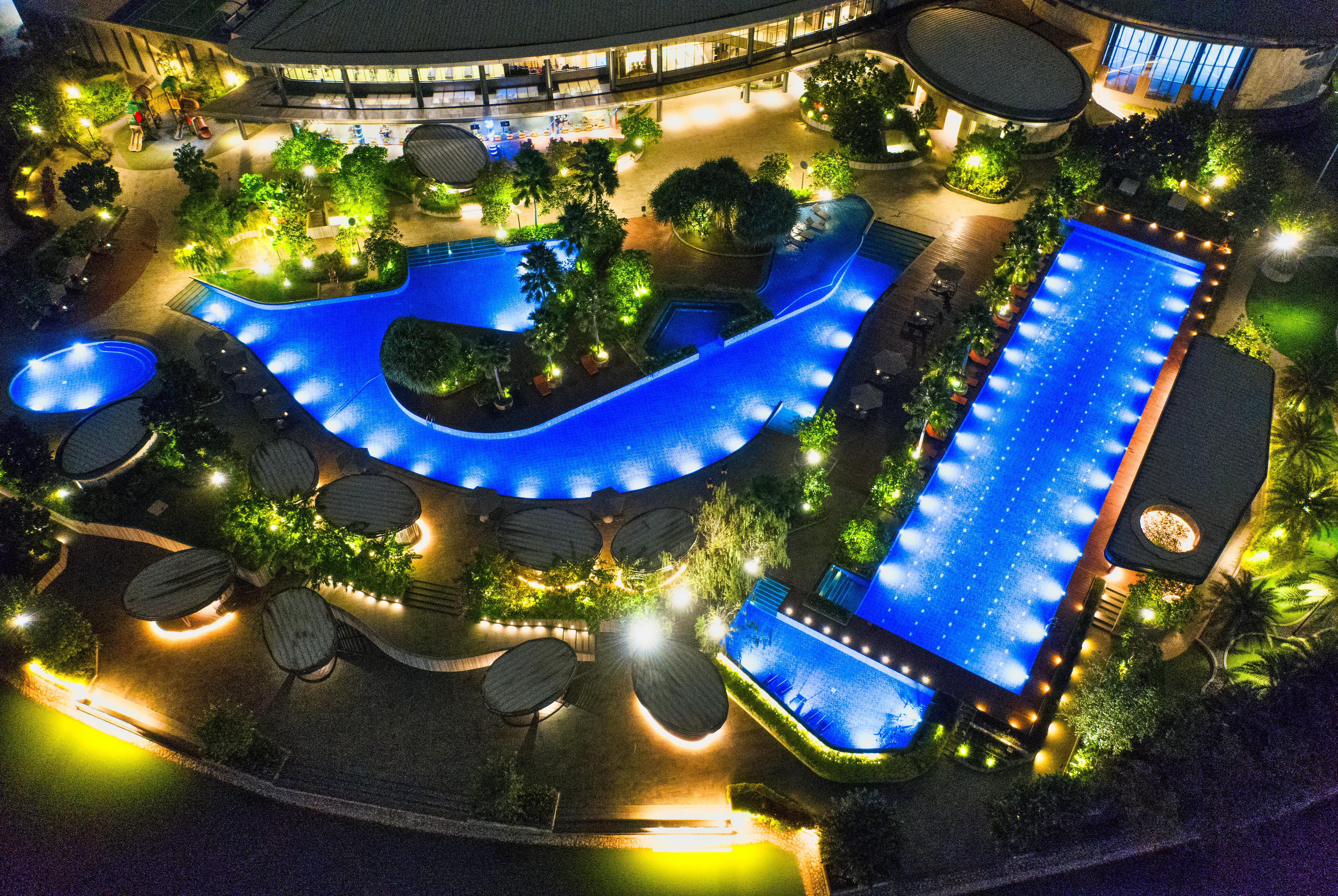 aerial photo of illuminated outdoor swimming pools in various shapes at night