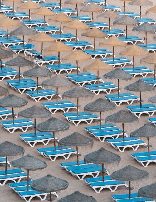 Free Aerial view of neatly arranged beach loungers and straw umbrellas on a sandy beach in Portugal. Stock Photo