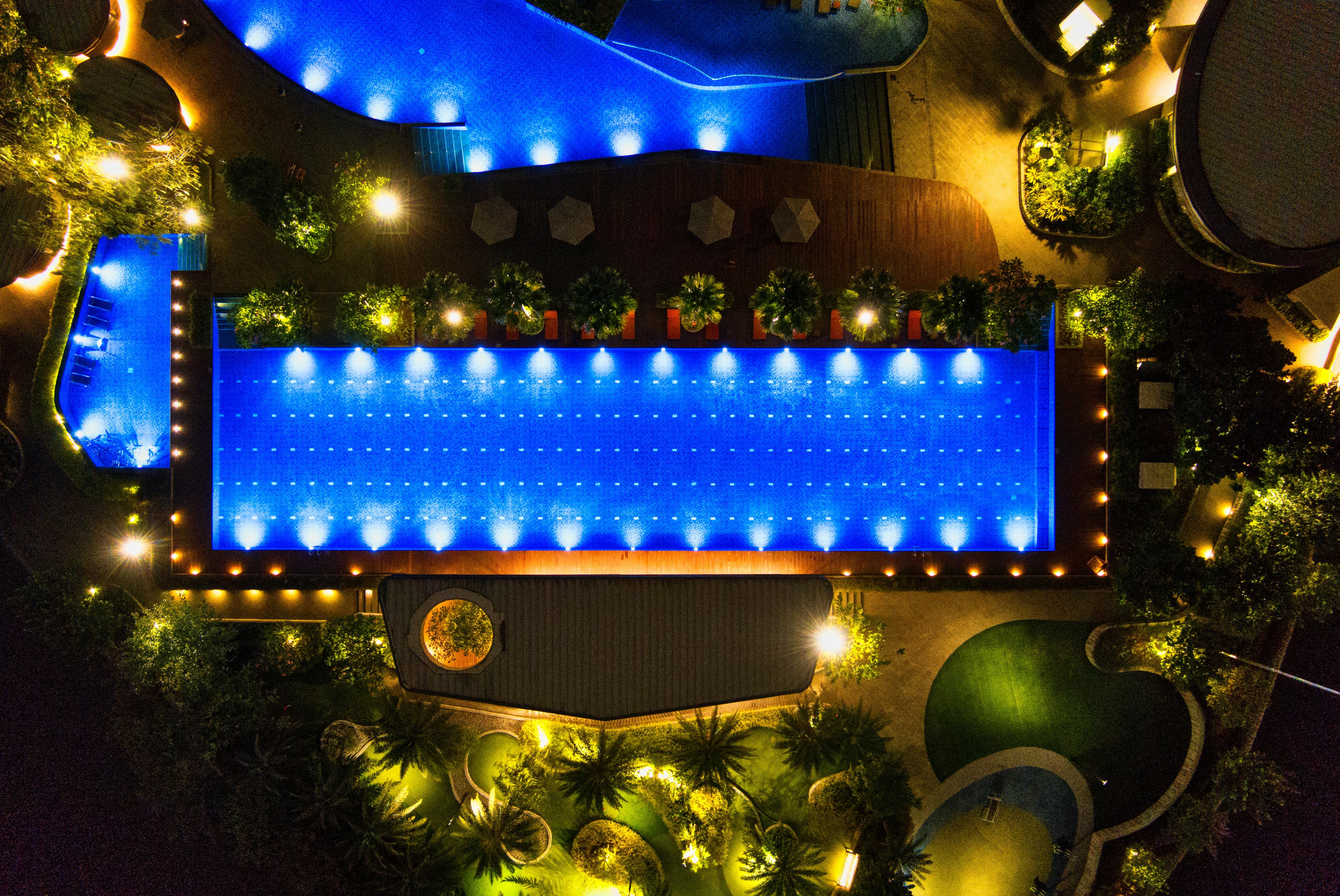 top view of a garden poolside area with multi shaped illuminated swimming pools