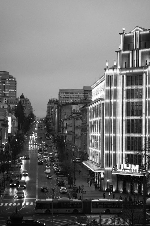 Free Black and white photo of a bustling city street with cars and illuminated buildings. Stock Photo
