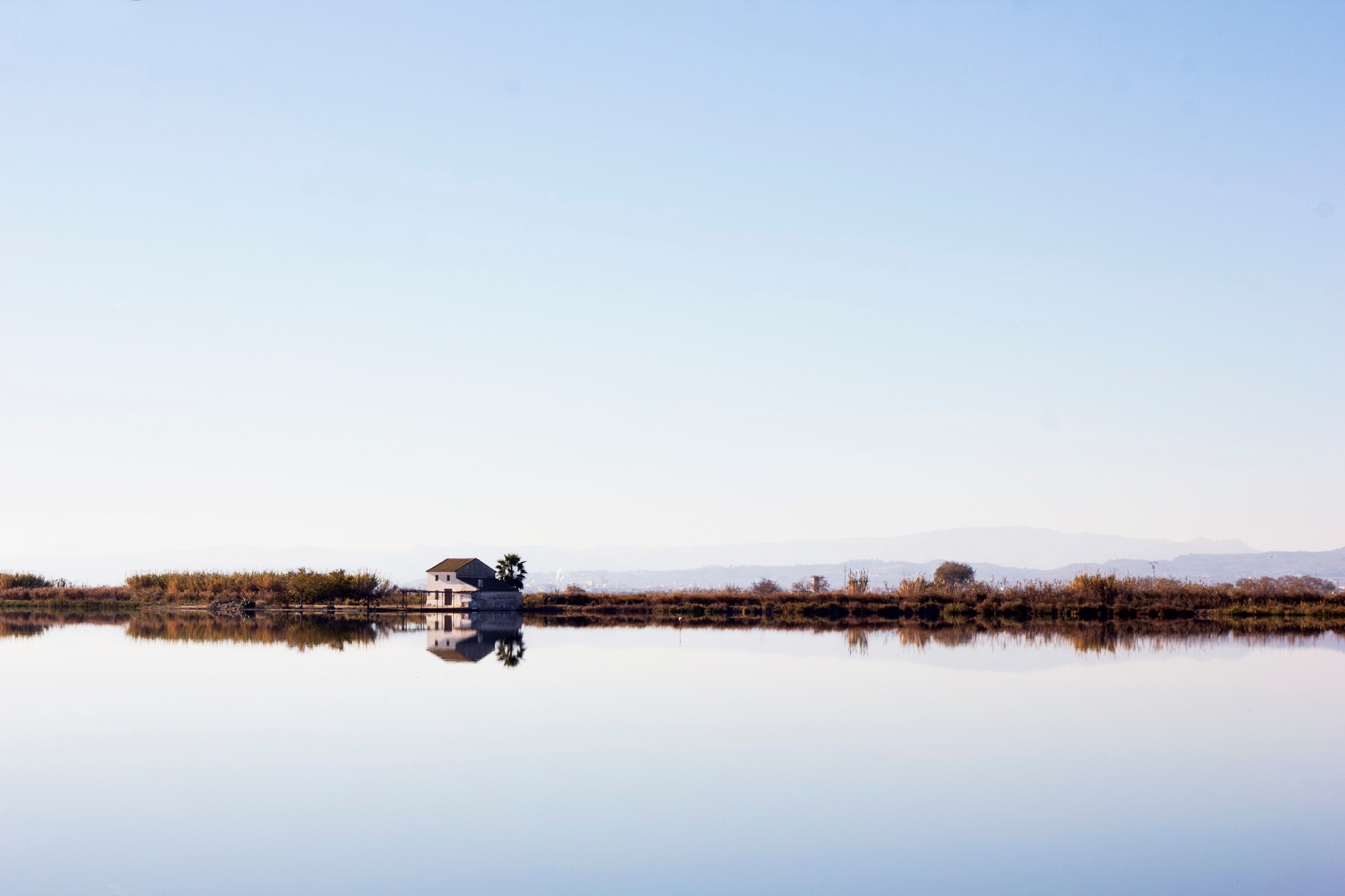 Serene house reflection in Albufera, Valencia capturing peaceful waters and clear sky.