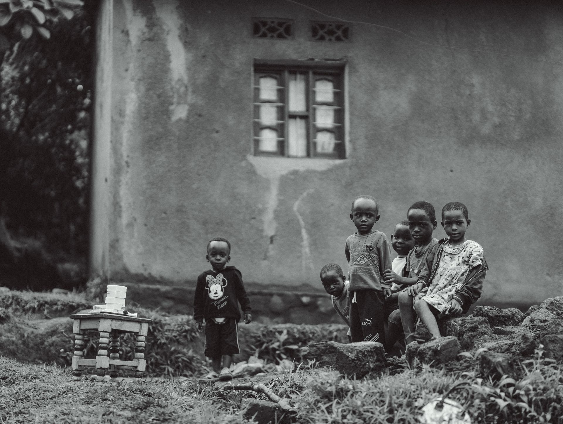 Group of children standing by a house in a rural setting, showcasing community life.