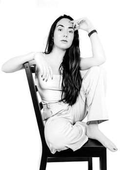 Elegant black and white portrait of a woman sitting on a chair, exuding confidence.