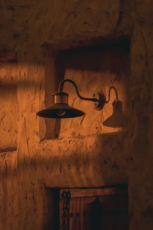 Free Warm glow of a vintage lamp on sandstone wall, capturing Dubai's rustic charm. Stock Photo