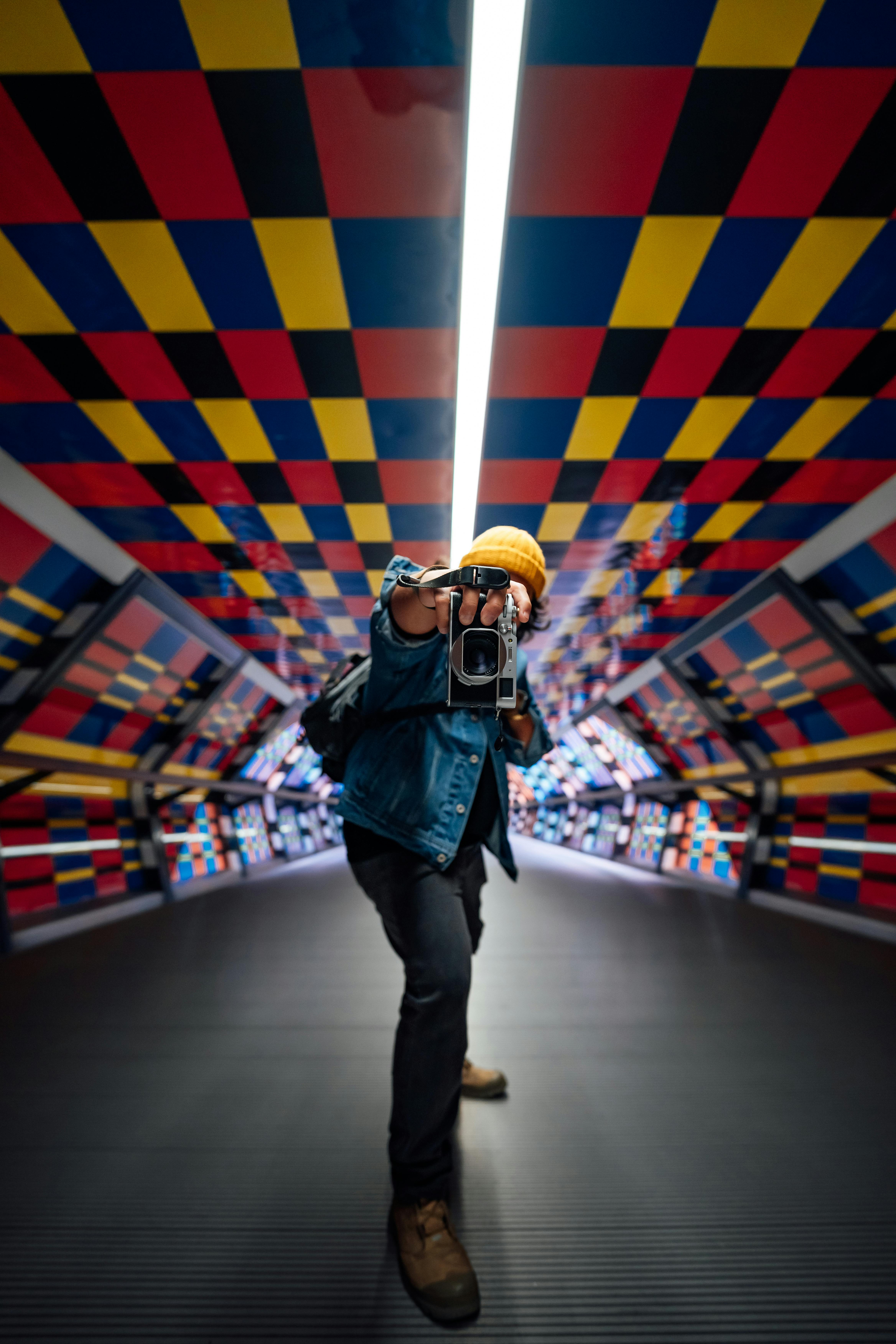 A person in a vibrant tunnel in London capturing a photo with a vintage camera.