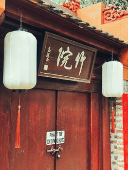 Rustic Asian wooden door with Chinese characters and lanterns, evoking tradition.