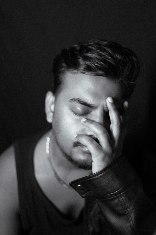 Free A moody black-and-white portrait of a reflective young man in a leather jacket. Stock Photo