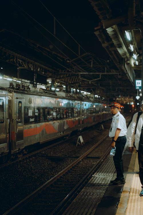 Free Night scene at a Jakarta train station with arriving train and staff in uniform. Stock Photo