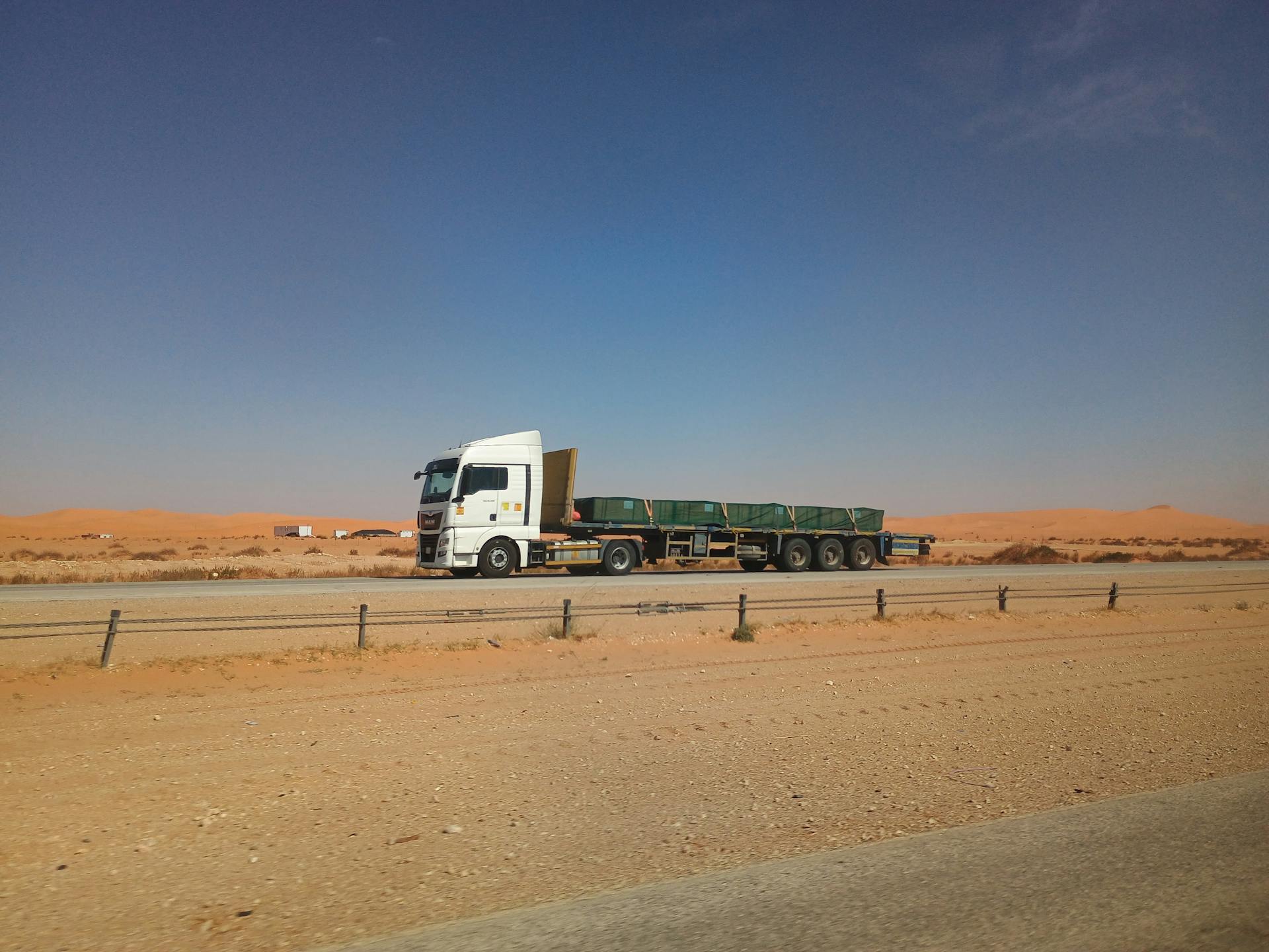 Flatbed truck on a desert highway in Eastern Province, Saudi Arabia under a clear sky.