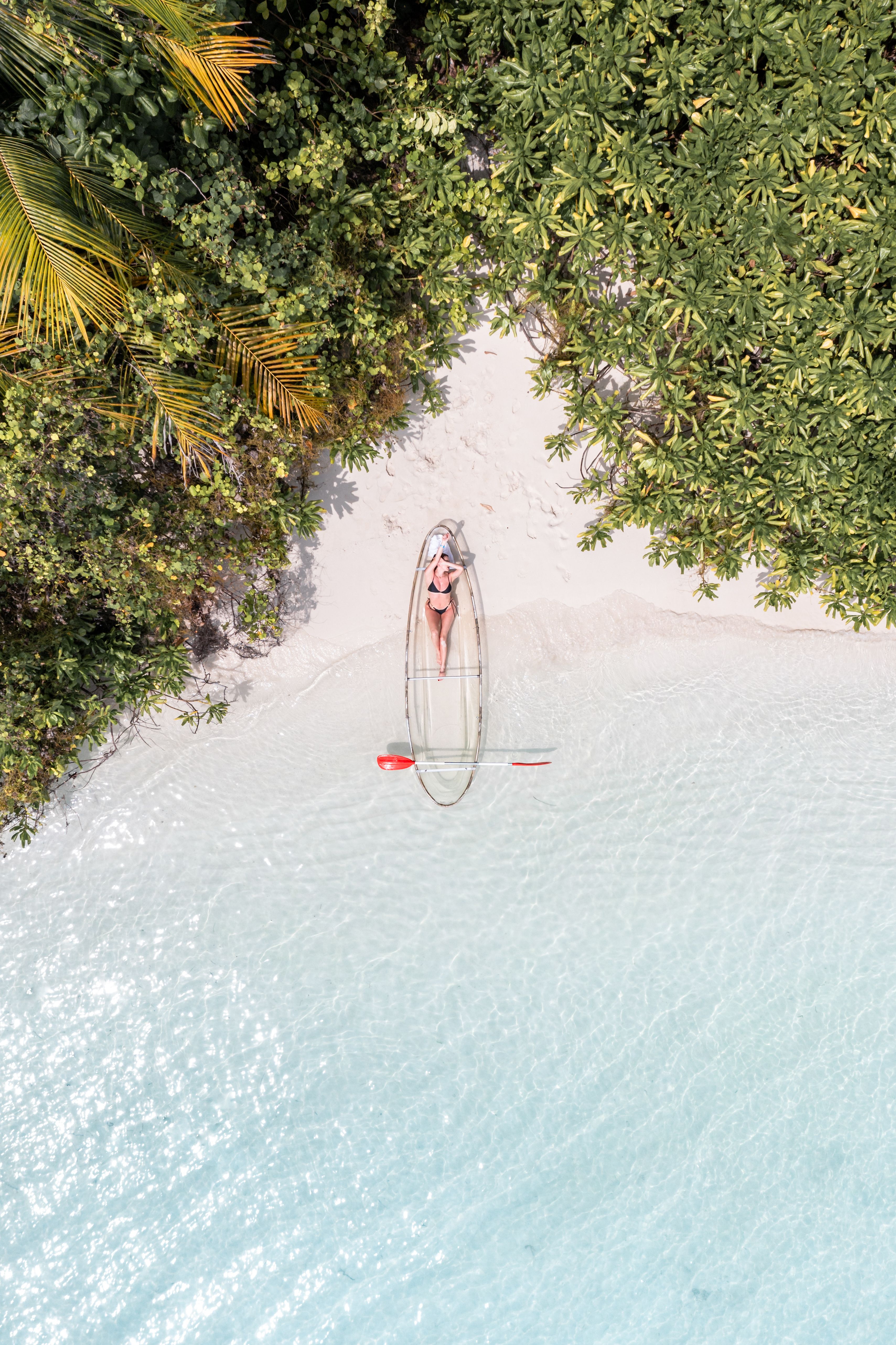 Clear kayak floating on pristine beach water in the Maldives.