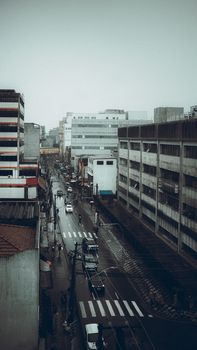 A moody urban street view with wet roads and a cloudy sky in a busy city.