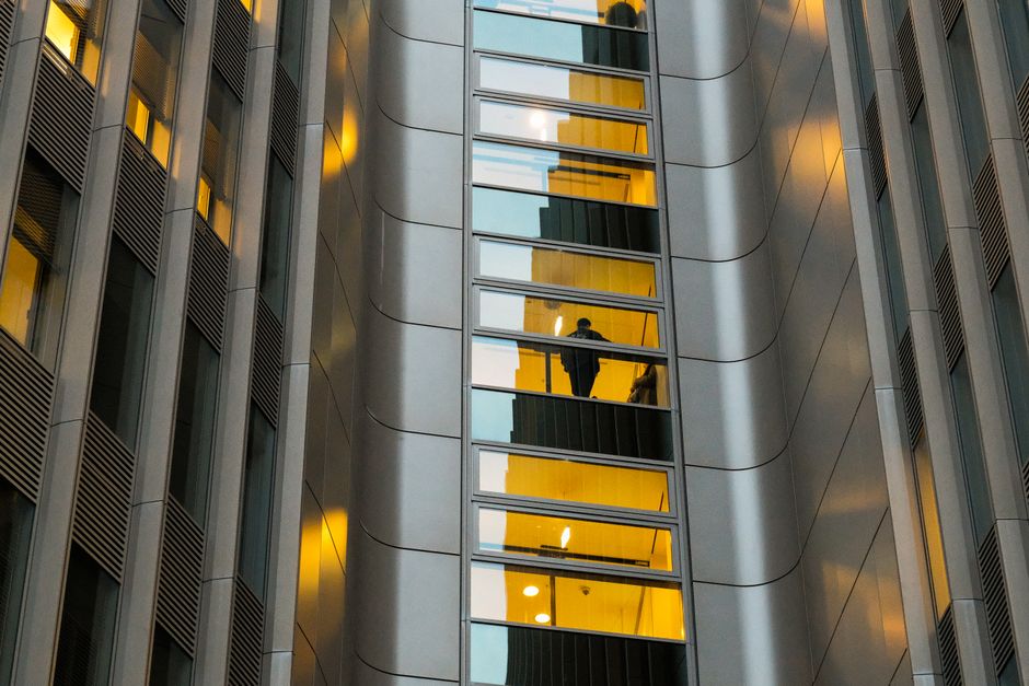 Reflection of a person in a modern Berlin building's glass facade with sleek architecture.