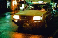 东京的雨夜，一辆黄色出租车行驶在街道上