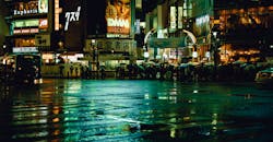 夜晚，东京的街道在雨中充满活力，霓虹灯标志反射在潮湿的人行道上