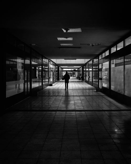 Free A solitary figure walks through a shadowed European hallway in Hamburg. Stock Photo