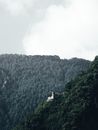 郁郁葱葱的森林山坡上，一座僻静的教堂坐落在多云的天空下