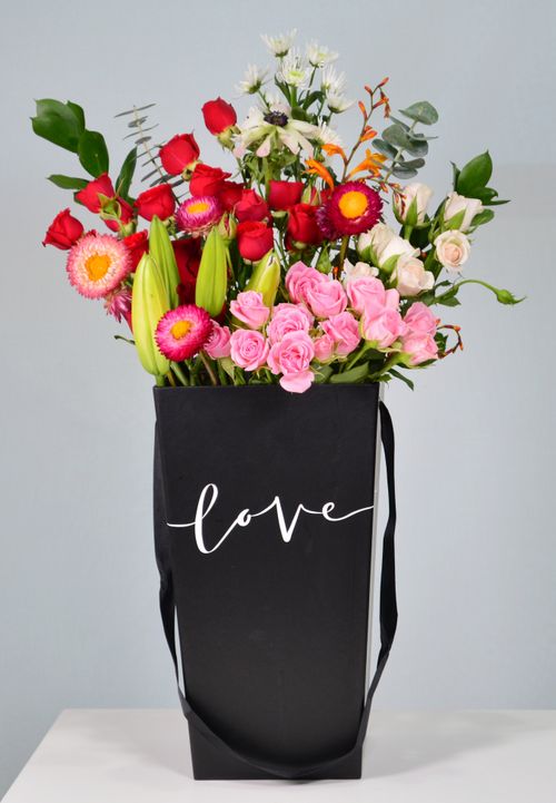 Free Colorful flower bouquet in a stylish black bag with 'love' inscription. Stock Photo