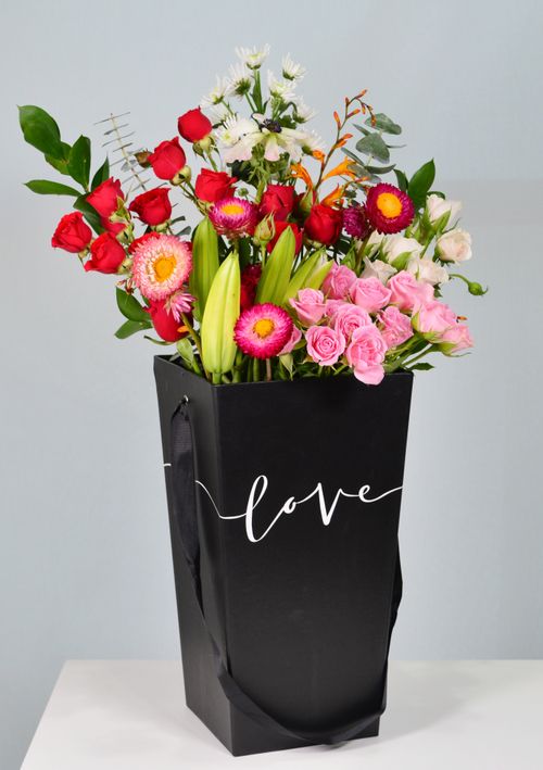 Free A colorful bouquet of various flowers elegantly arranged in a black bag labeled 'love'. Perfect for celebrations. Stock Photo