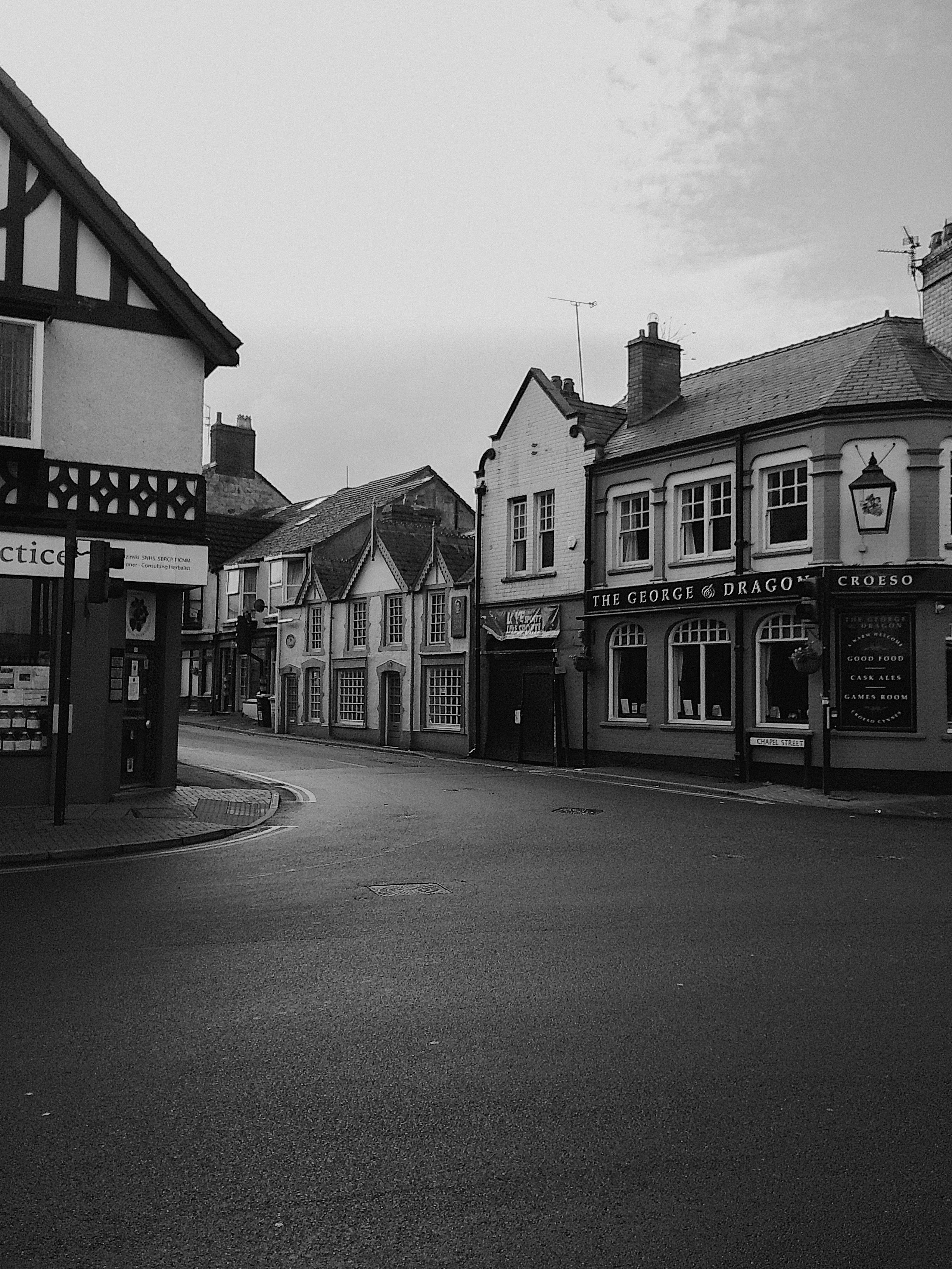 A serene black and white street view showcasing traditional Welsh architecture.