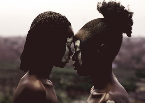 Two Topless Women Facing Each Other With Face Paint