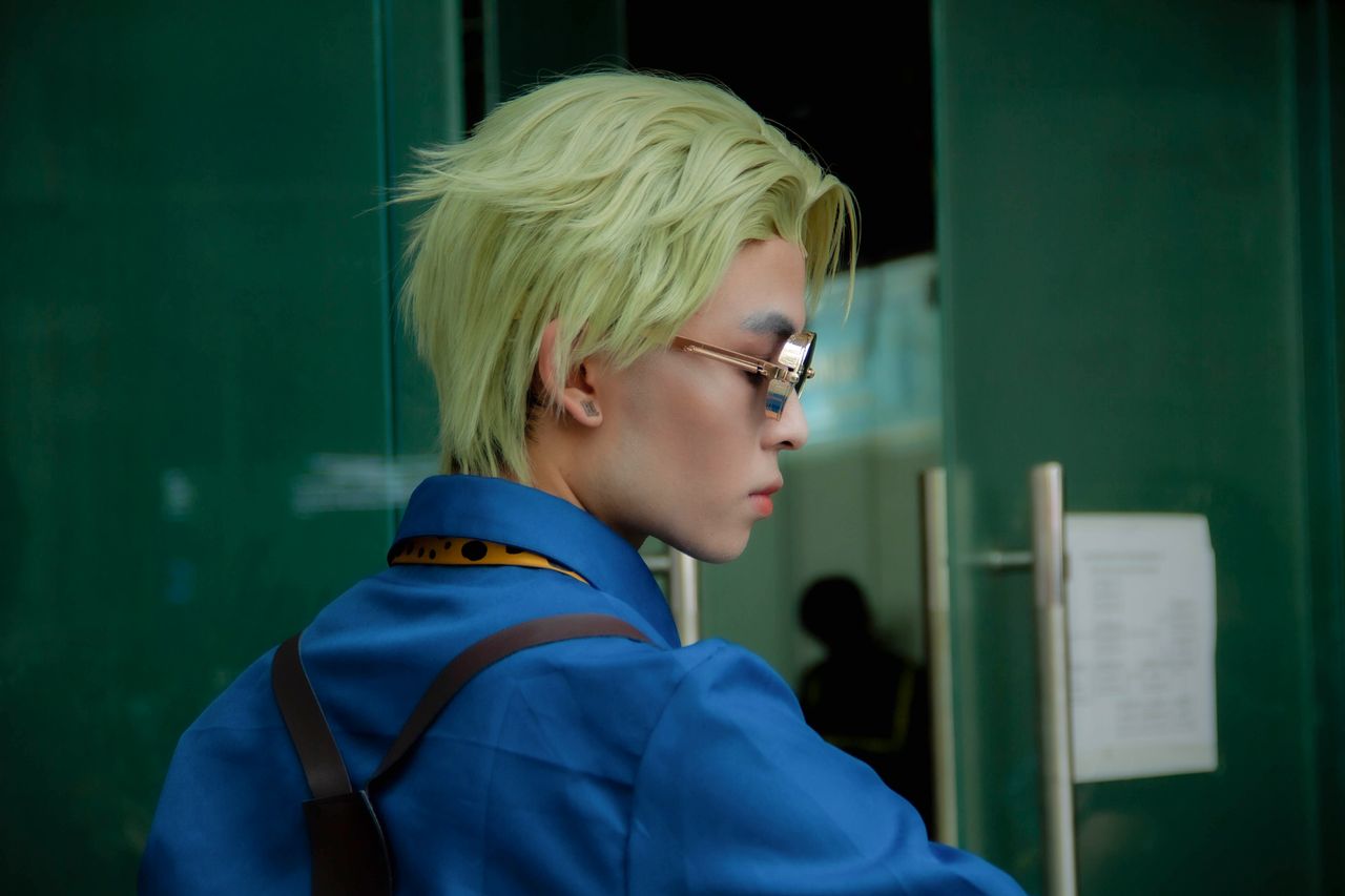 stylish person with blonde hair and glasses in a blue outfit showcasin