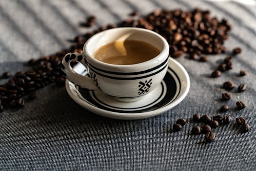 Fresh coffee served in a patterned ceramic mug surrounded by scattered coffee beans.