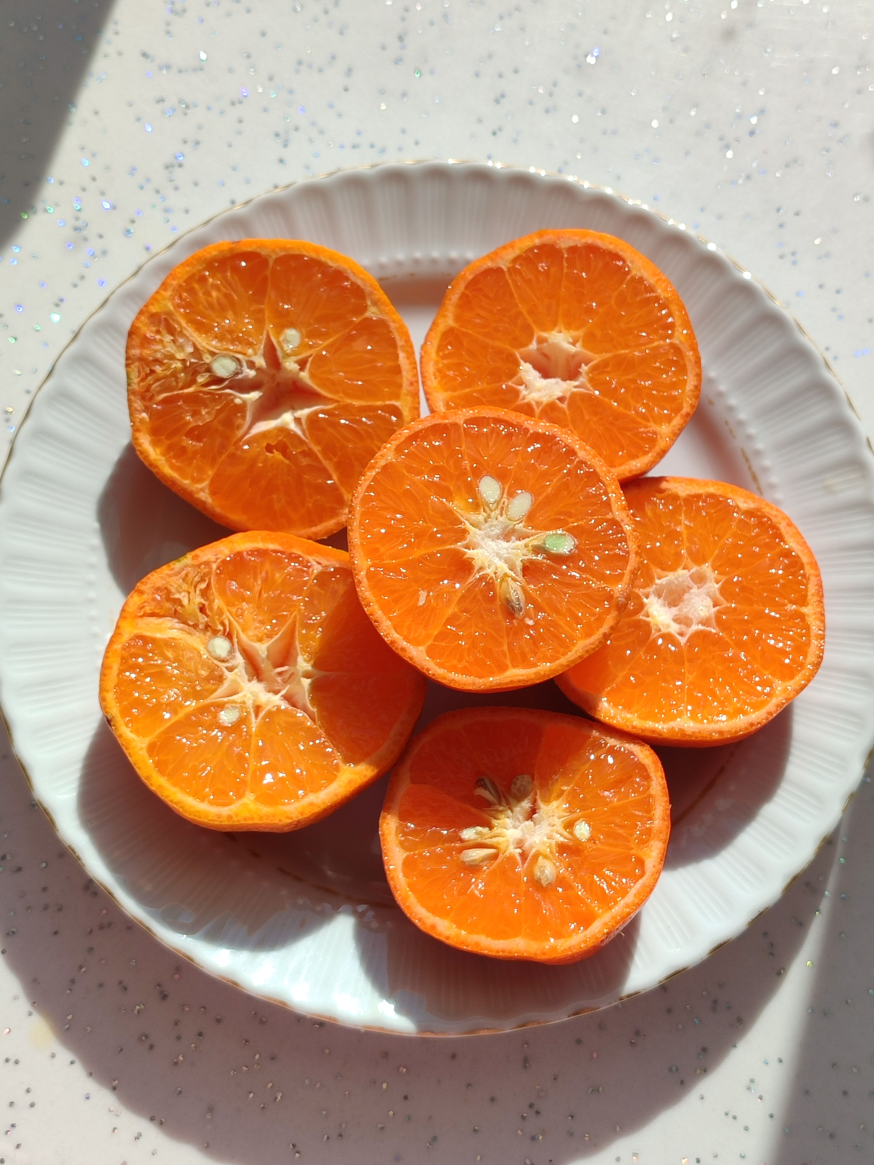 Vibrant orange slices on a white plate, illuminated by sunlight, perfect for culinary stock images.
