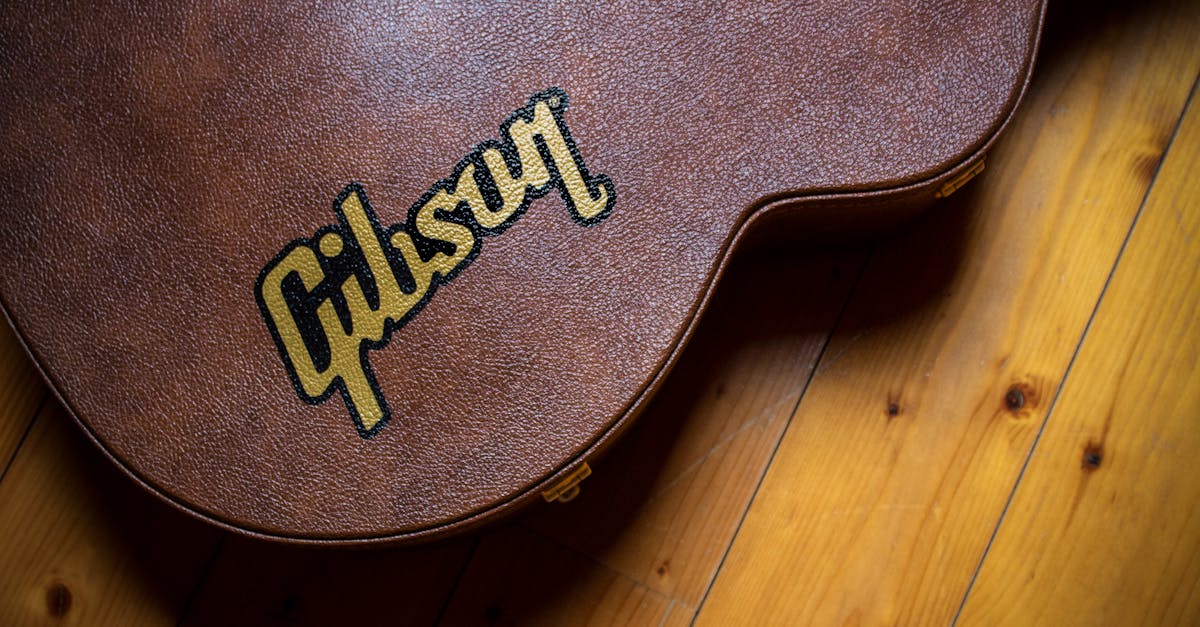 A close shot of a brown guitar case with 'Gibson' logo, placed on a wooden floor.