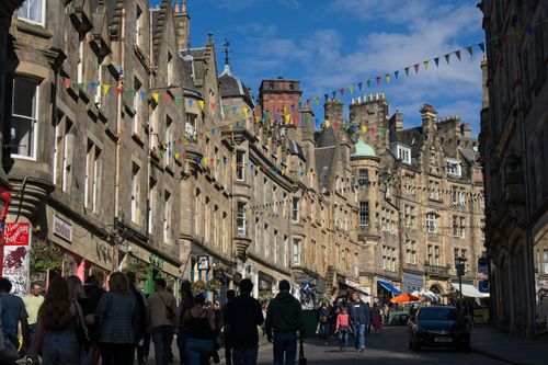 Free Colorful street view of Edinburgh, Scotland, capturing lively architecture and city life under a bright sky. Stock Photo