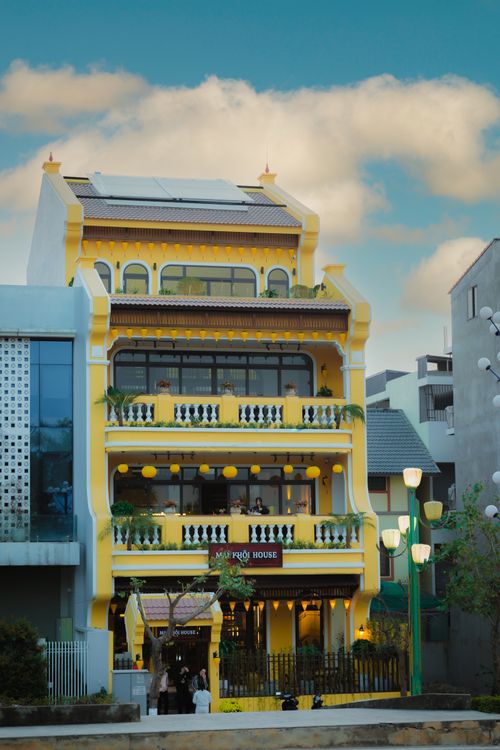 Free Charming yellow colonial style building against a bright blue sky, showcasing architectural elegance. Stock Photo