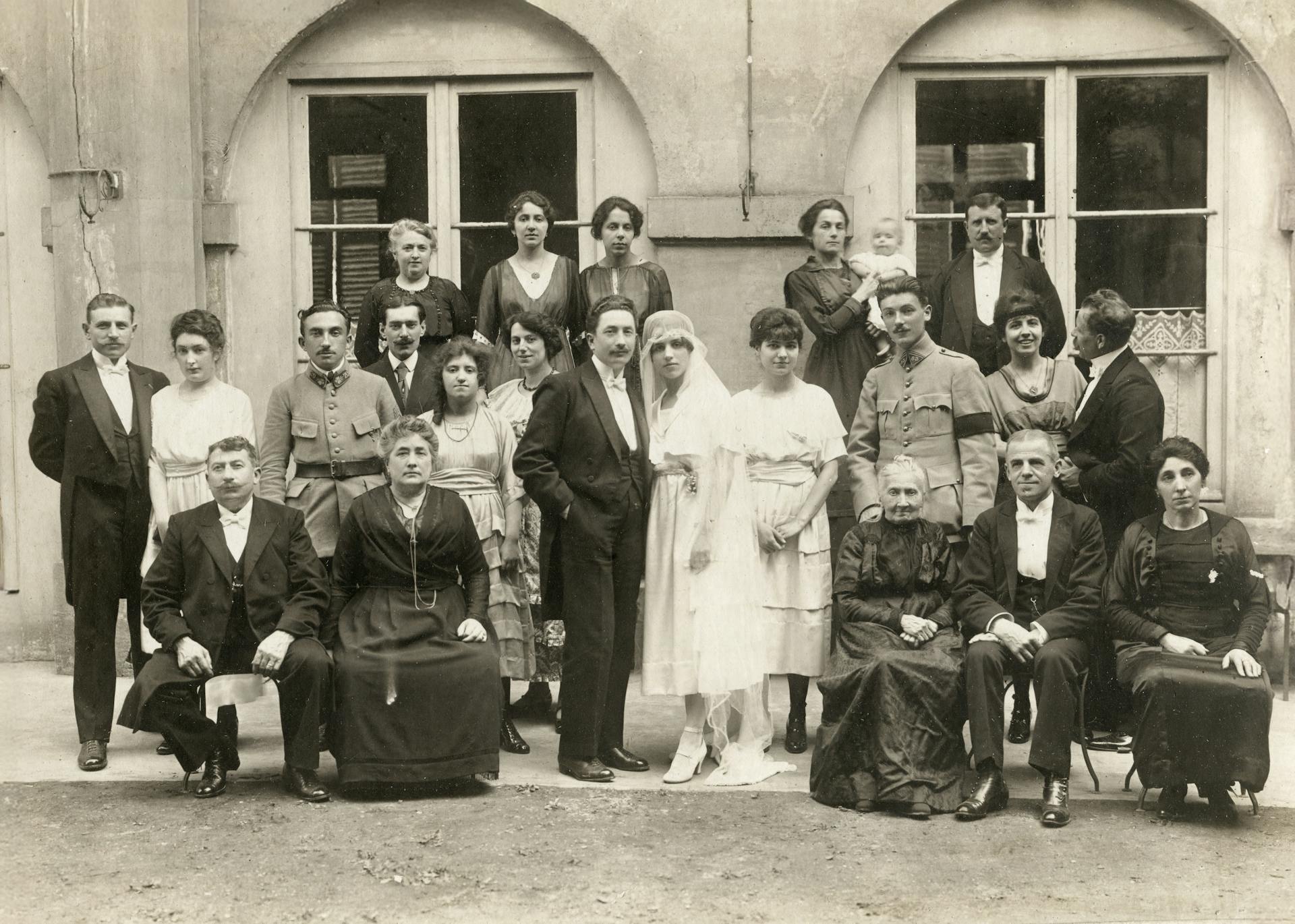 Black and white vintage photo of a wedding group with multiple generations posing outdoors.