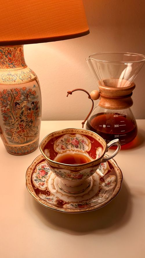Free A decorative teacup and Chemex coffee maker on a table with a vintage lamp. Stock Photo
