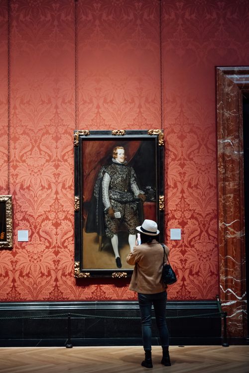 Free A visitor examines a historical portrait in a museum with ornate decor. Stock Photo