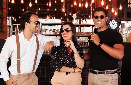 Three stylish adults enjoying time at a trendy urban bar with ambient lighting.